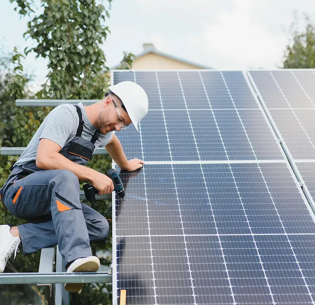 Un homme installe des panneaux solaires sur un support métallique, vissant un panneau à Vaureal dans le Val d'Oise 95