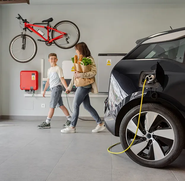 Famille rentrant chez elle, voiture électrique en charge dans un garage moderne à Vauréal dans le Val-d’Oise 95