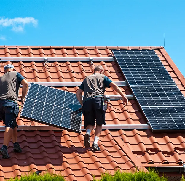 Deux hommes installent des panneaux solaires sur un toit en tuiles rouges à Vauréal dans le Val-d’Oise 95